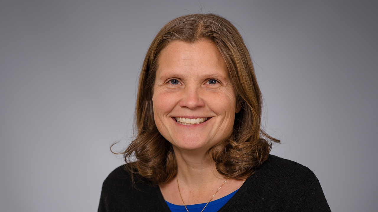 En leende kvinna i svart tröja och blå skjorta