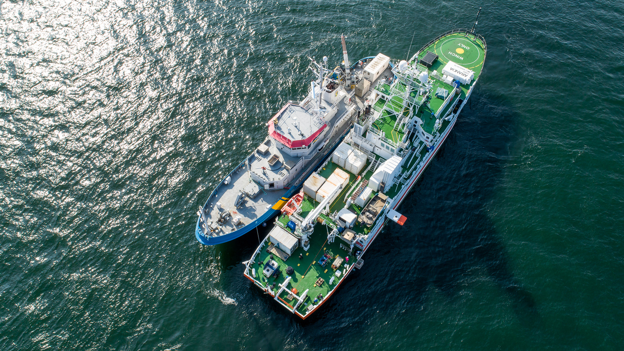 En drönarbild på två stora forskningsfartyg som ligger sida vid sida på öppet hav