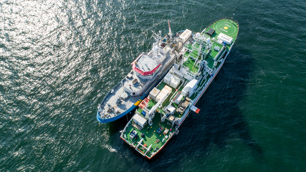 En drönarbild på två stora forskningsfartyg som ligger sida vid sida på öppet hav