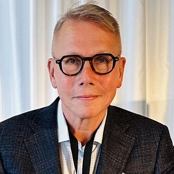 En kostymklädd man sitter vid ett bord.