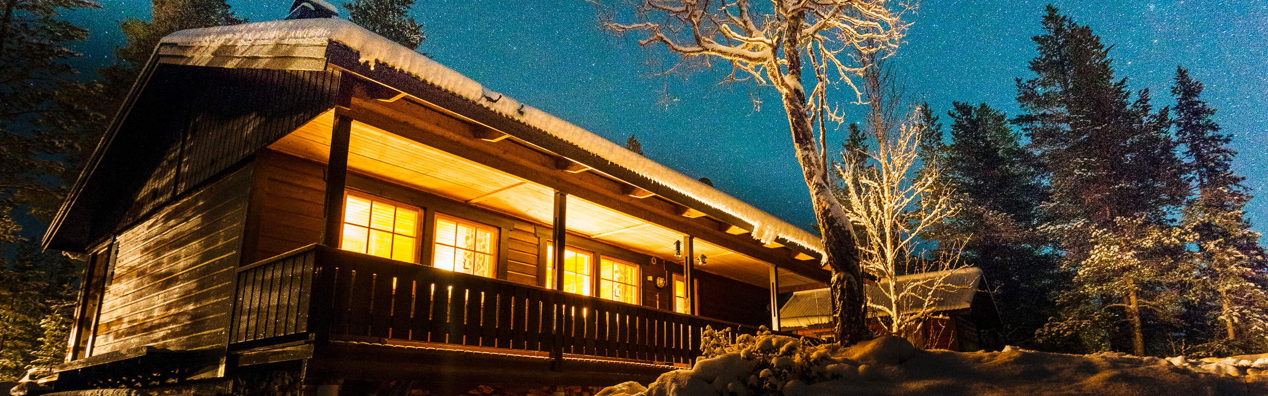 Upplyst fjällstuga under stjärnhimmel