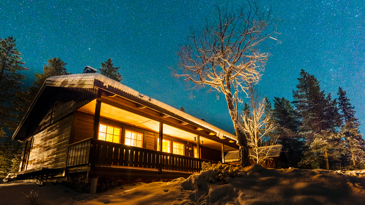 Upplyst fjällstuga under stjärnhimmel