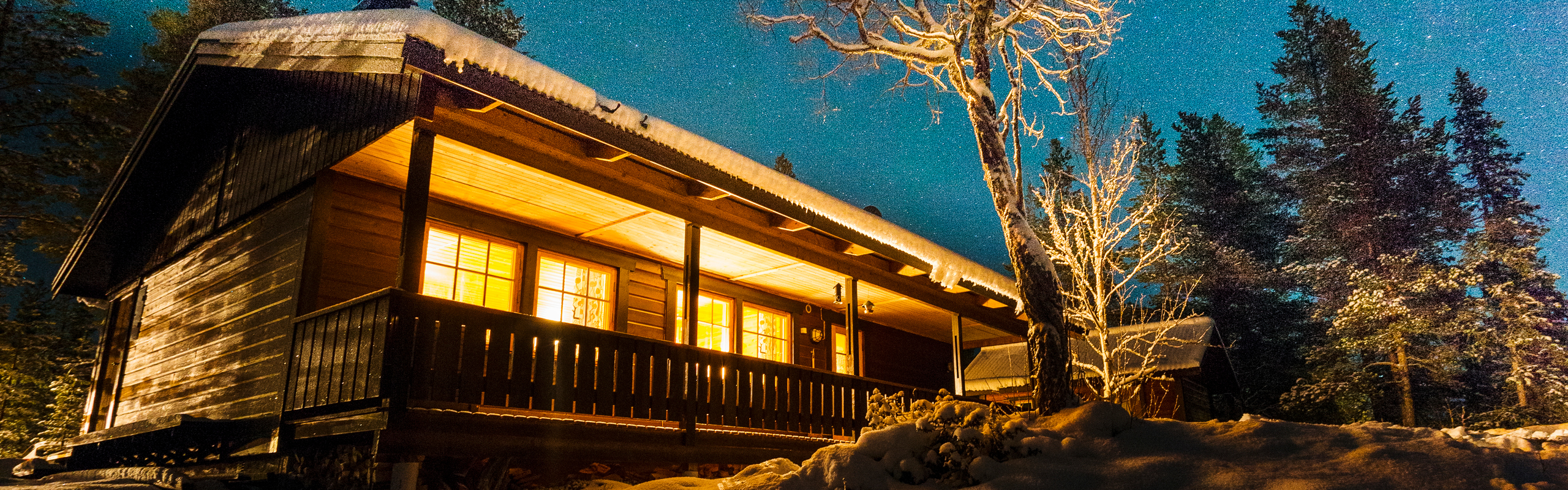 Upplyst fjällstuga under stjärnhimmel