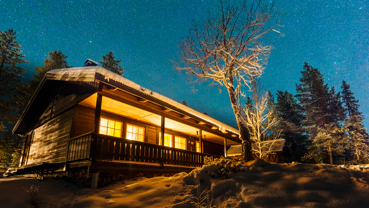 Upplyst fjällstuga under stjärnhimmel