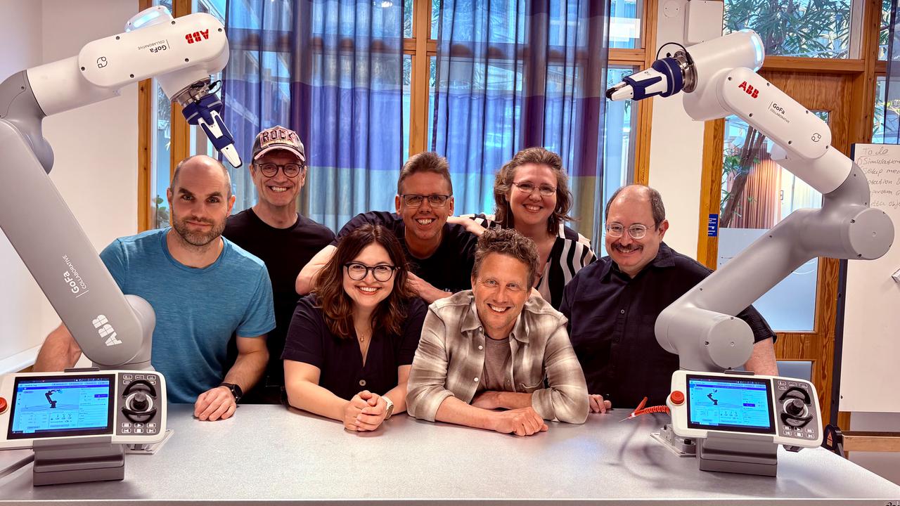 En grupp människor som poserar för en bild med robotarmar.