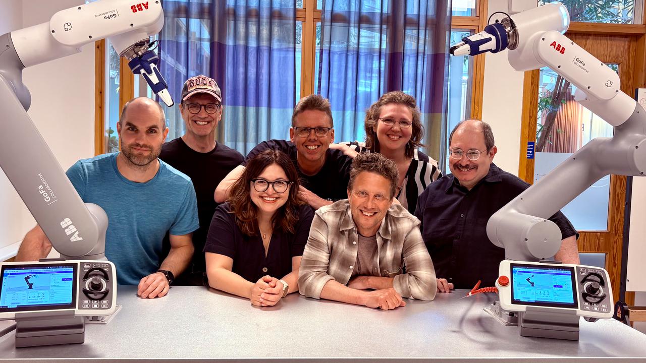 En grupp människor som poserar för en bild med robotarmar.