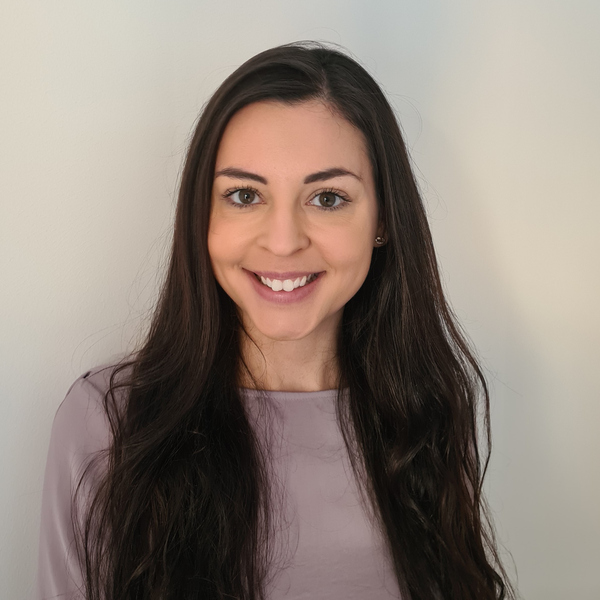 En kvinna med långt mörkt hår som ler mot kameran