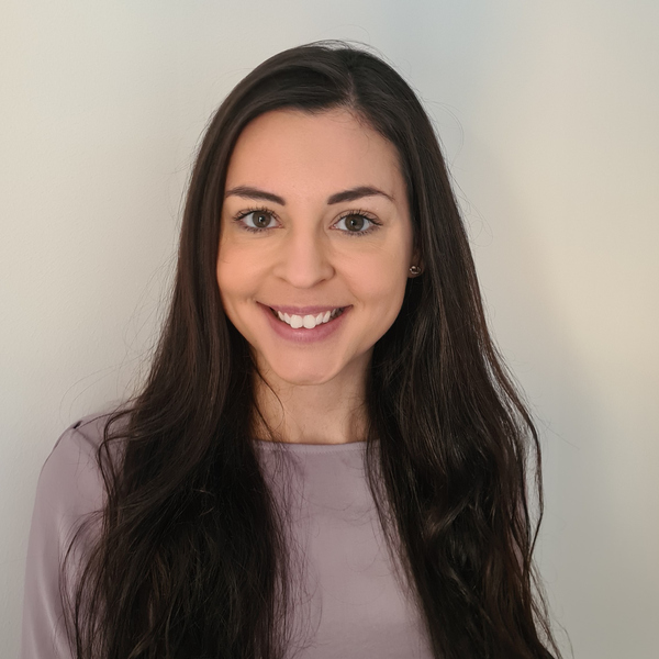 En kvinna med långt mörkt hår som ler mot kameran