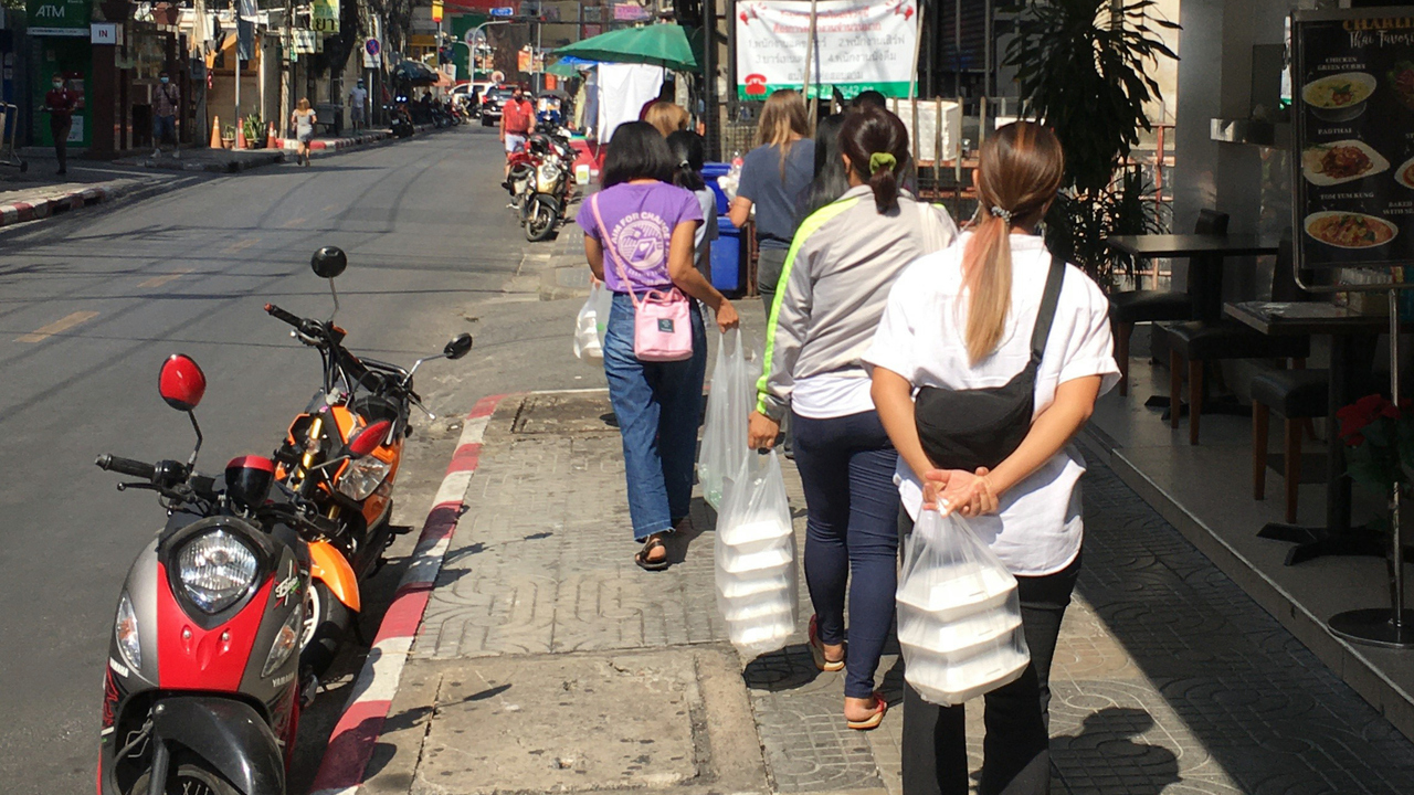 Personer med matpåsar går längs en gata.