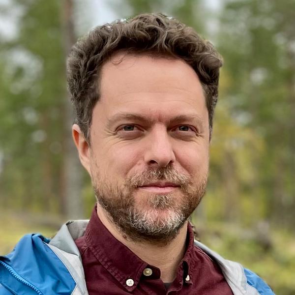 Två män som står bredvid varandra i en skog.