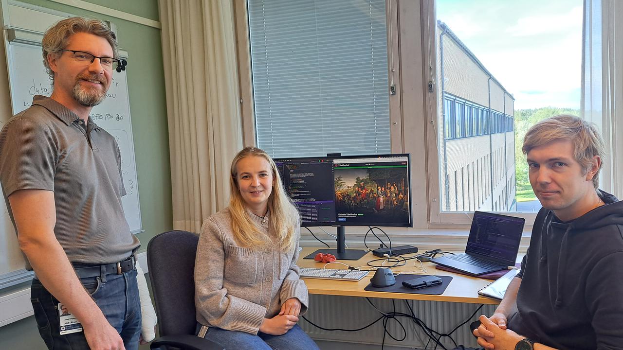 Två män och en kvinna sitter framför en whiteboard.