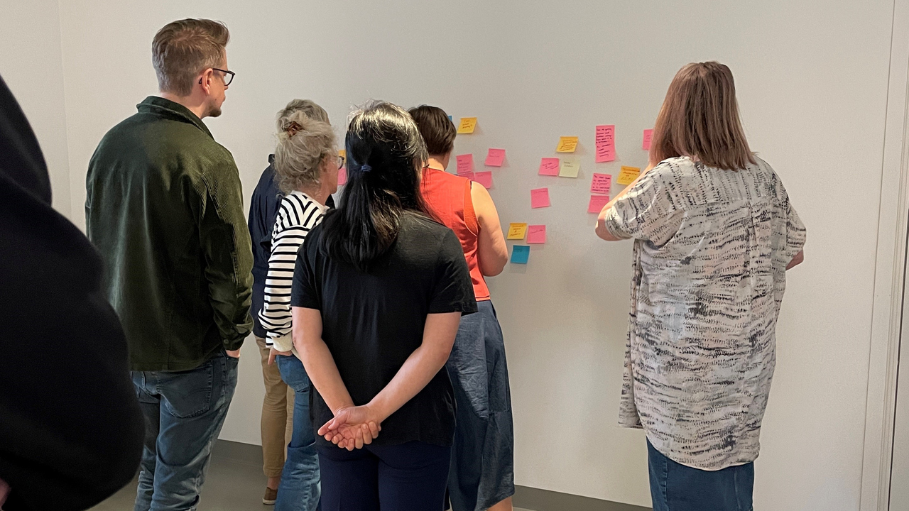 Forskare som diskuterar post-it lappar på en vägg.