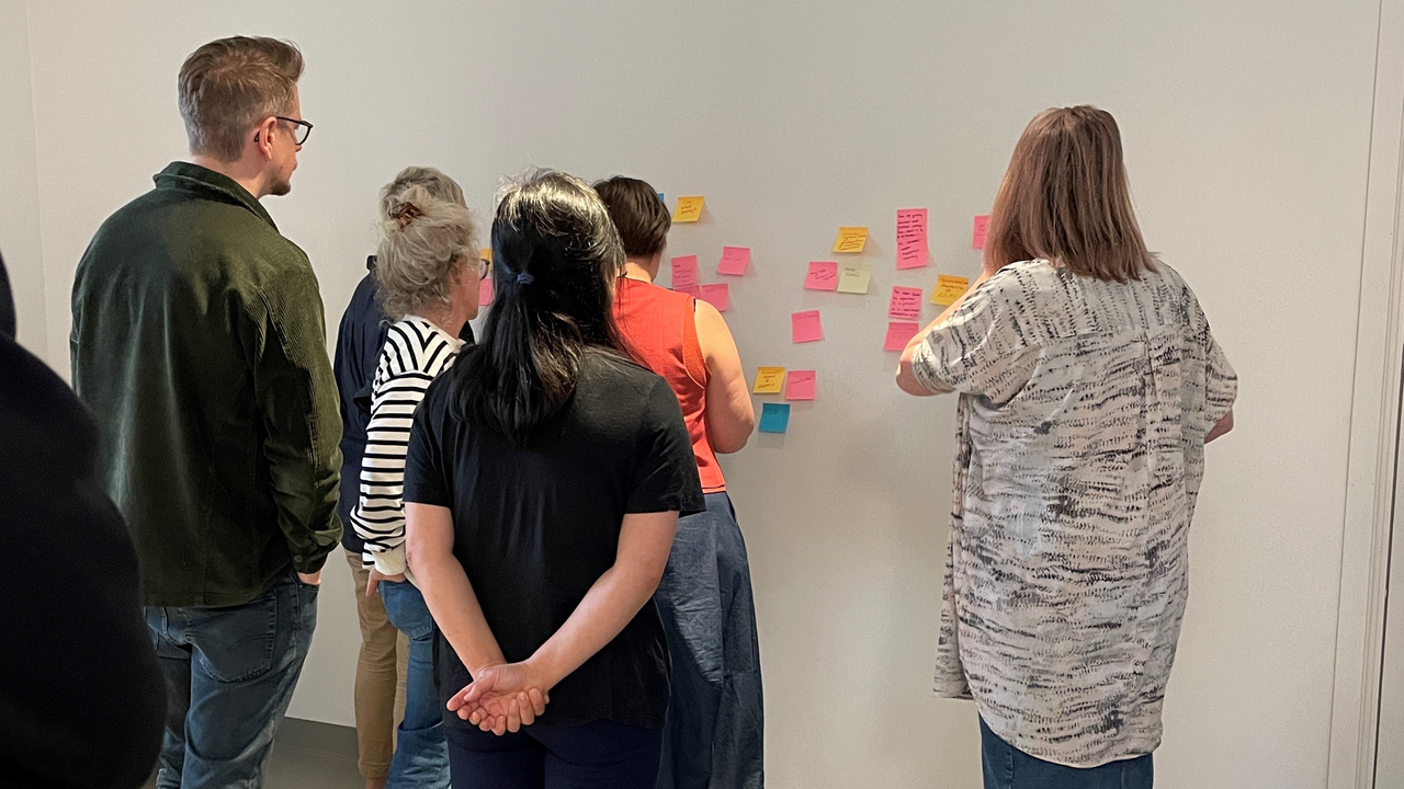 Forskare som diskuterar post-it lappar på en vägg.