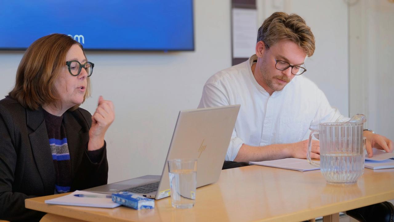 Två personer sitter vid ett bord med en bärbar dator.