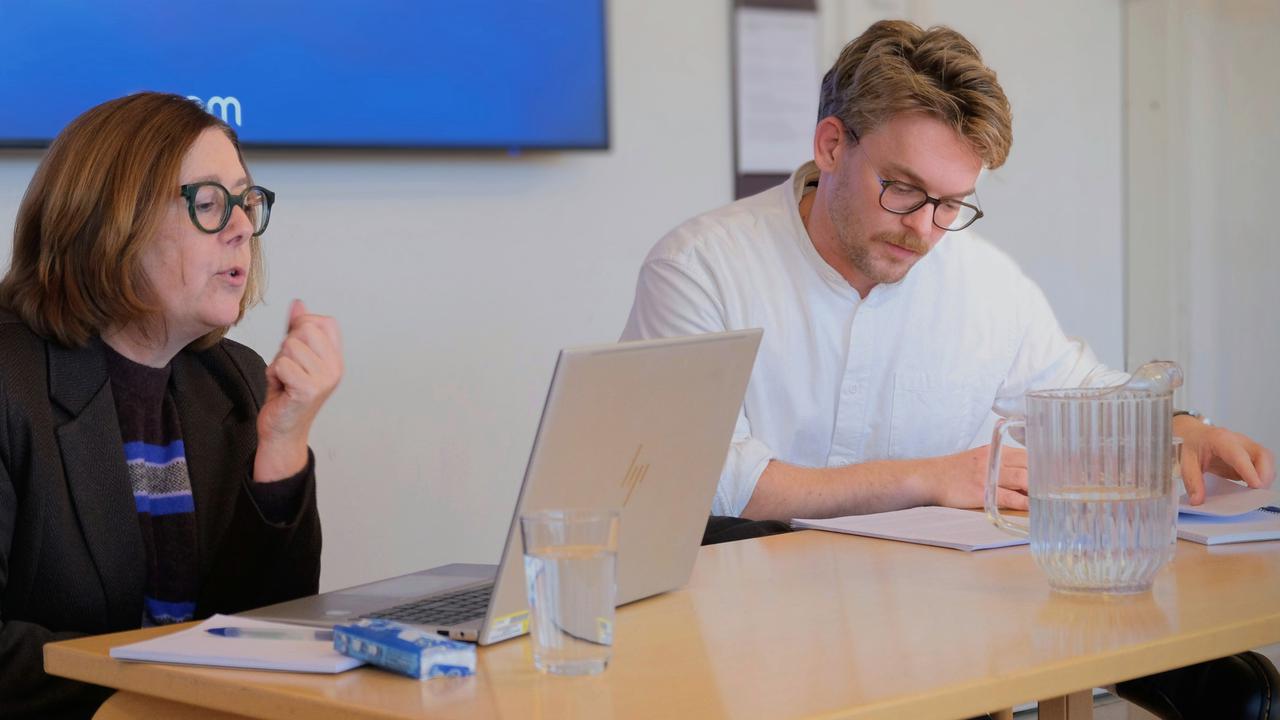 Två personer sitter vid ett bord med en bärbar dator.