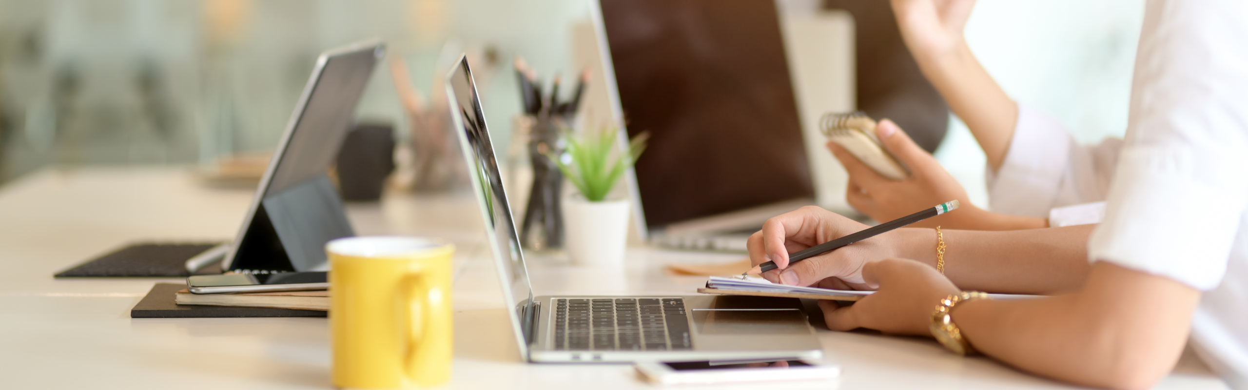 Detaljbild från ett mötesrum med personer och datorer.