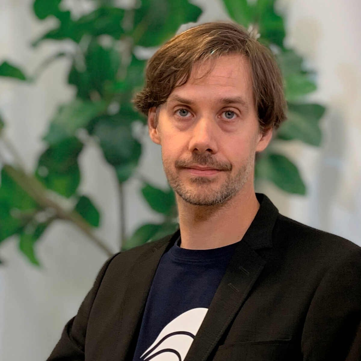 Porträtt på Johan Tordsson som sitter vid ett bord. I bakgrunden finns en växt