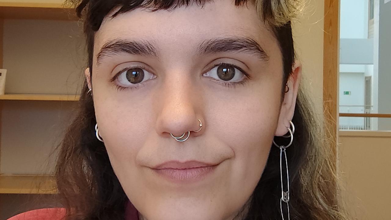 Kvinna med mörkt långt hår, kort lugg och röd skjorta.