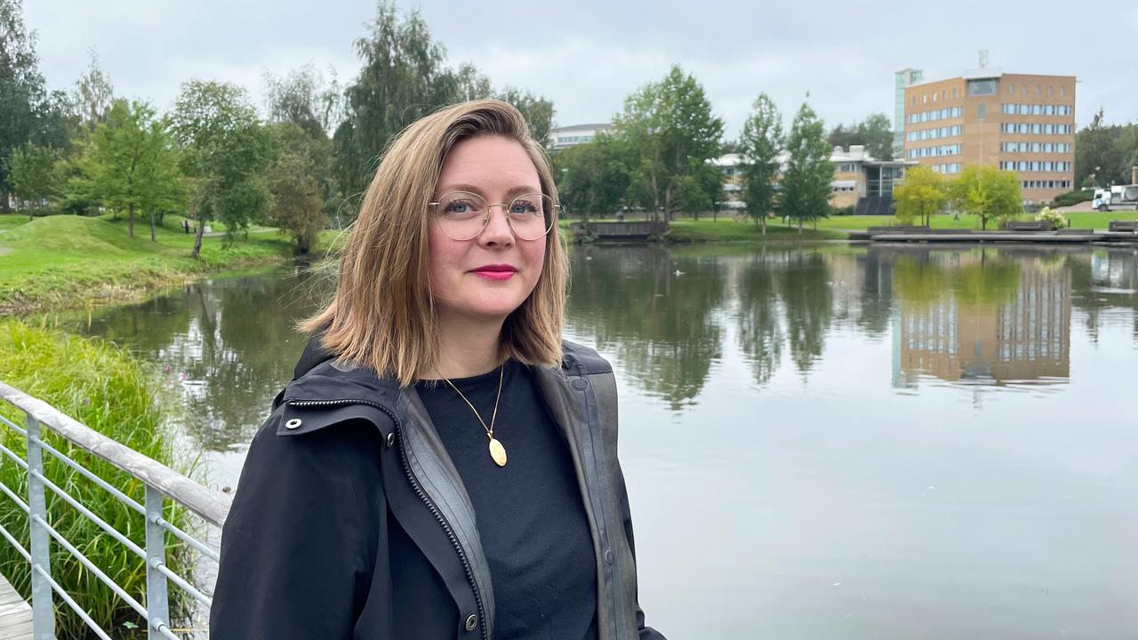 En kvinna står på en bro invid universitetsdammen.