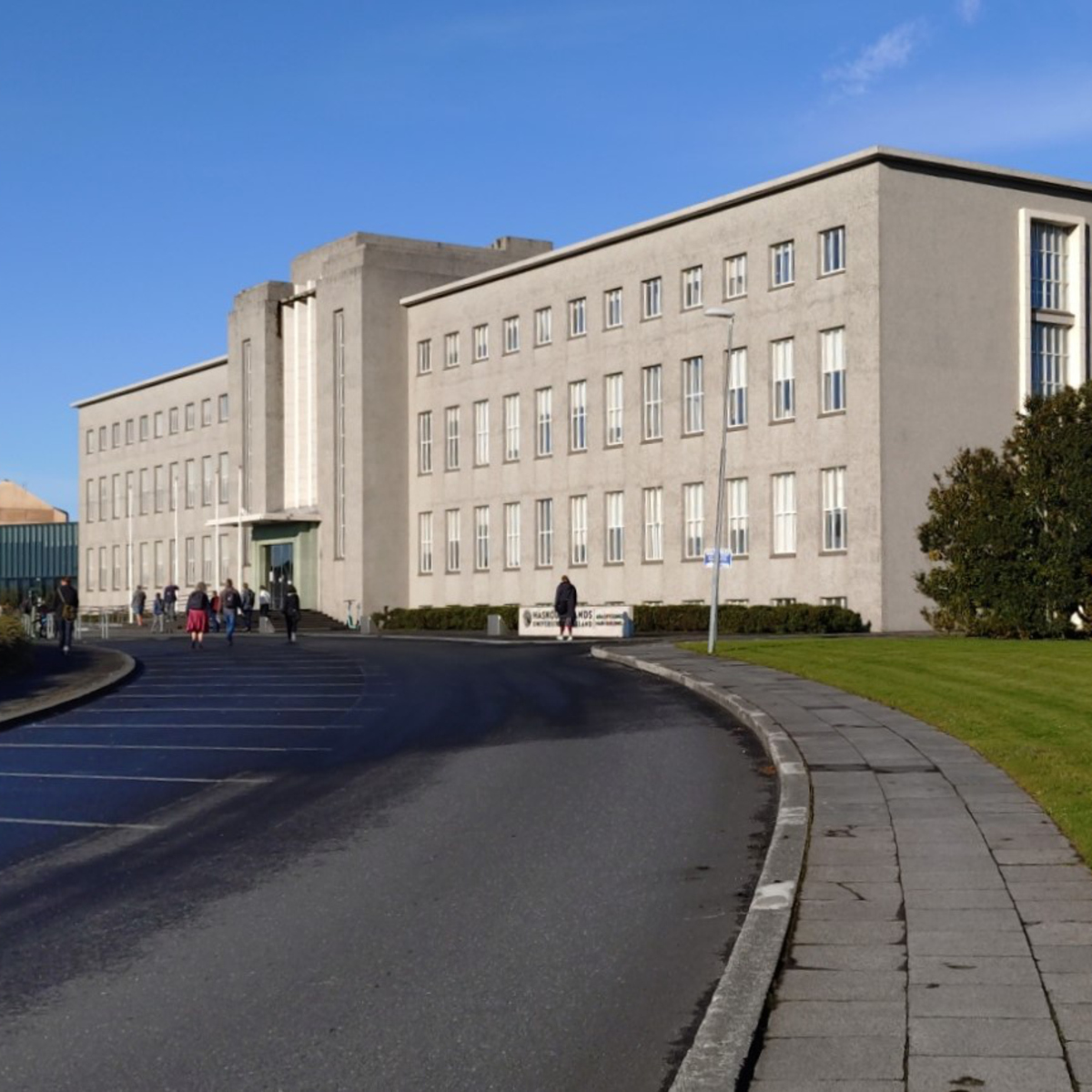 En stor grå byggnad som ligger vid sidan av en väg. Islands universitet.