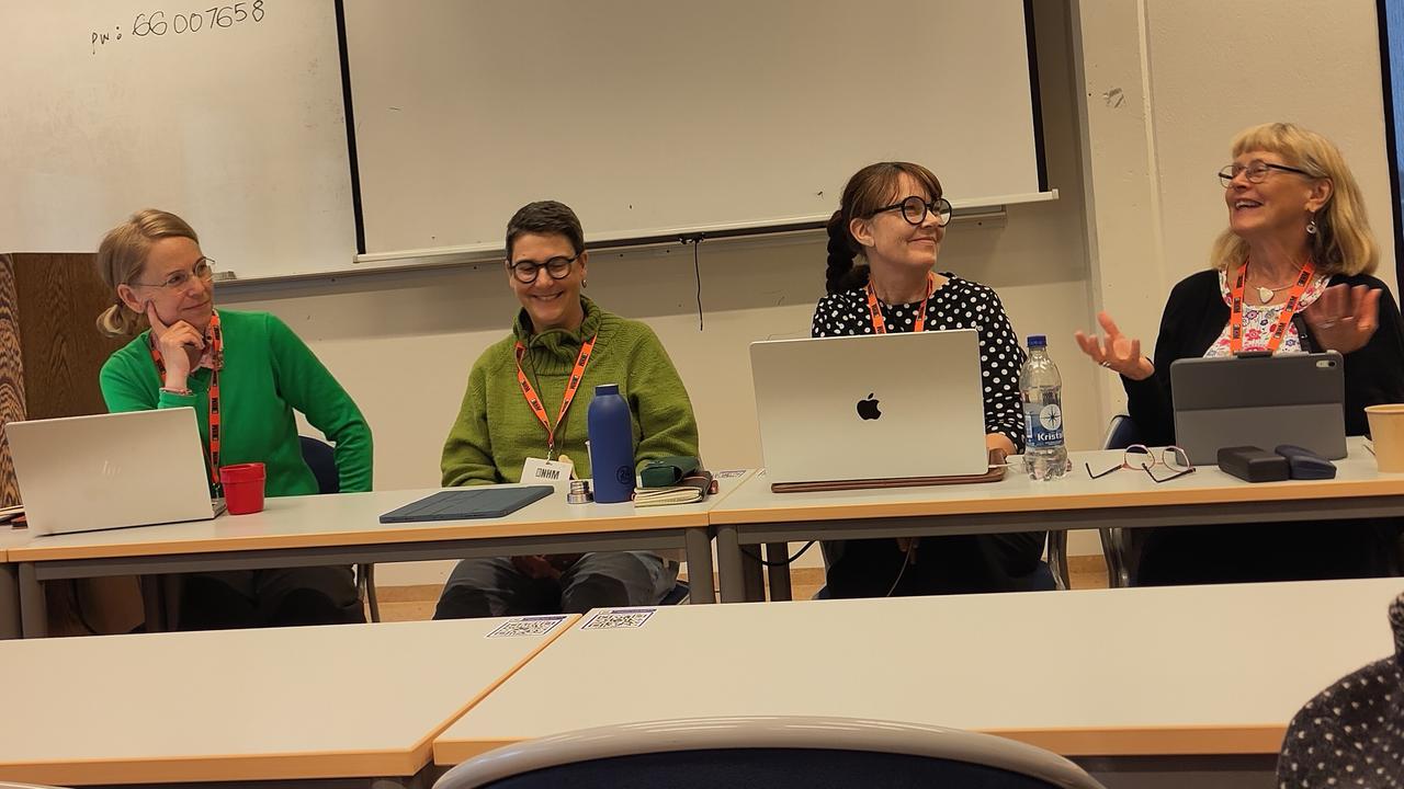 En grupp människor som sitter vid ett bord med bärbara datorer.