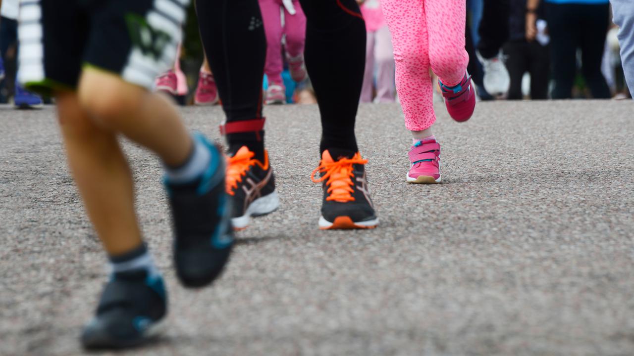 Fötter på personer i olika åldrar som springer på asfalt.