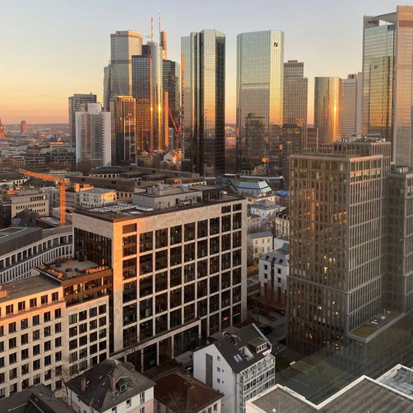 Utsikt genom kontorsfönstret över höghus i solnedgången. 