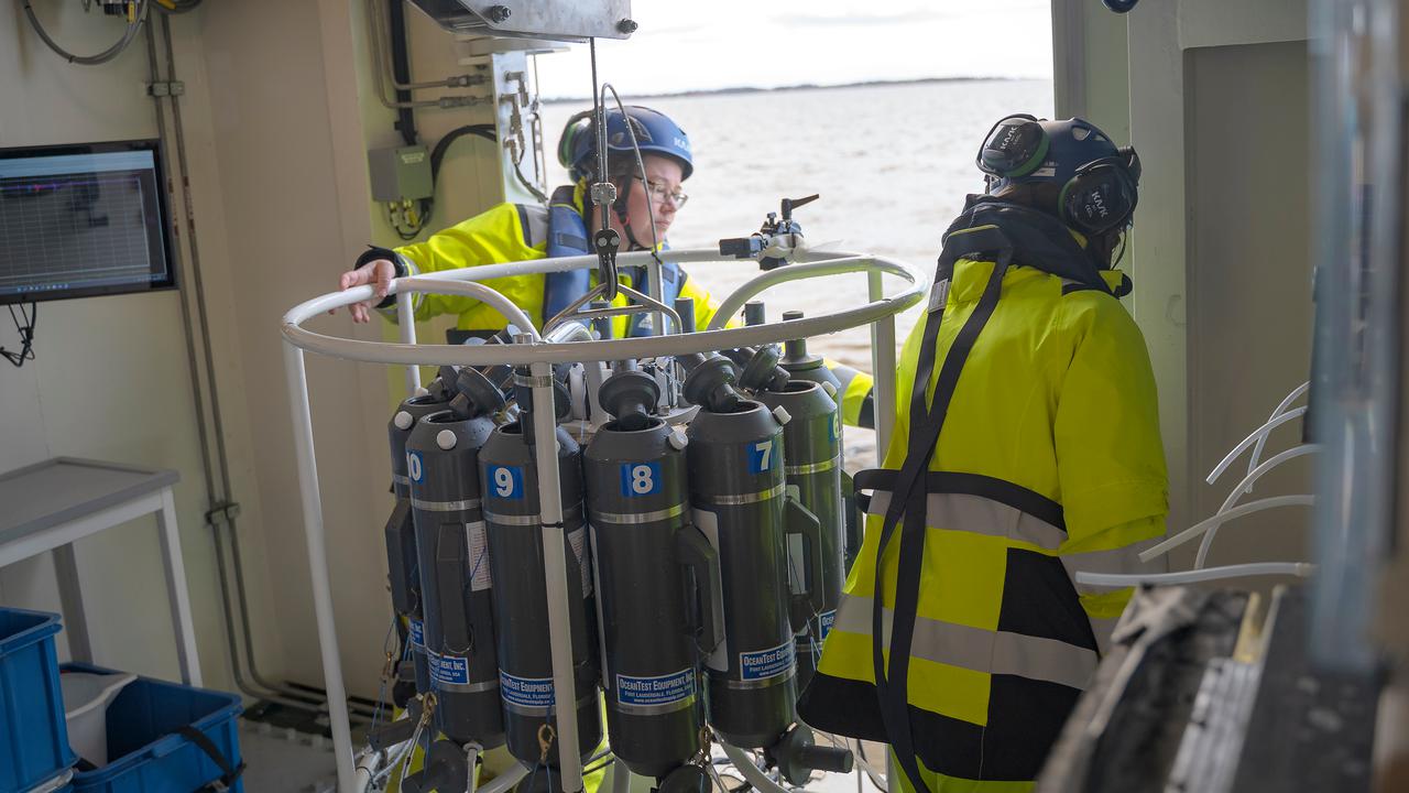 Två personer sjösätter en vattenprovtagare ombord på ett forskningsfartyg.