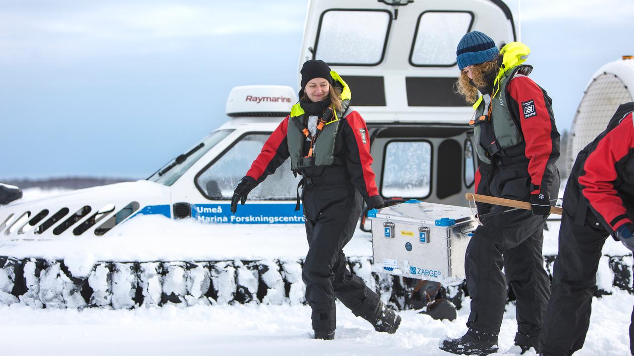 Personer som arbetar med provtagning på is med en svävare.