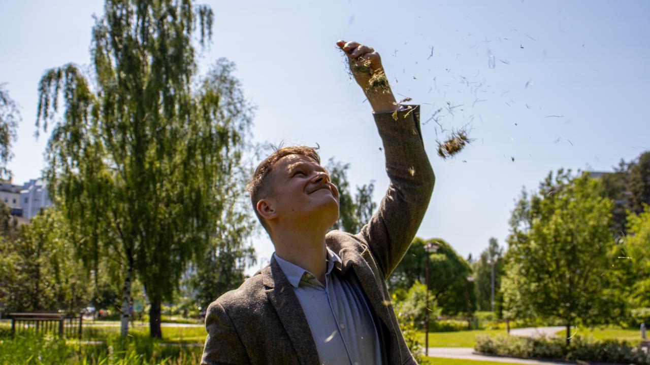 En man i kostym som kastar upp nyklippt gräs i luften.