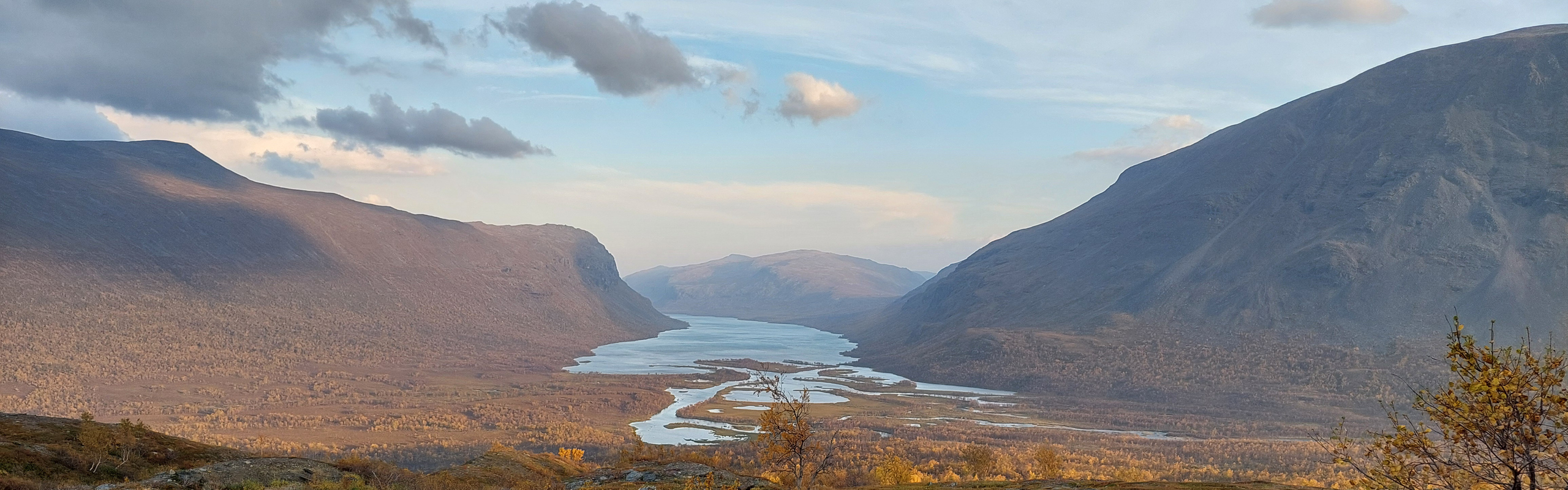 Vy över vattendrag genom fjällandskap.