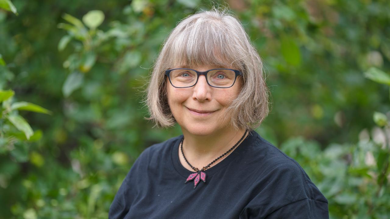 En kvinna med glasögon står framför träd