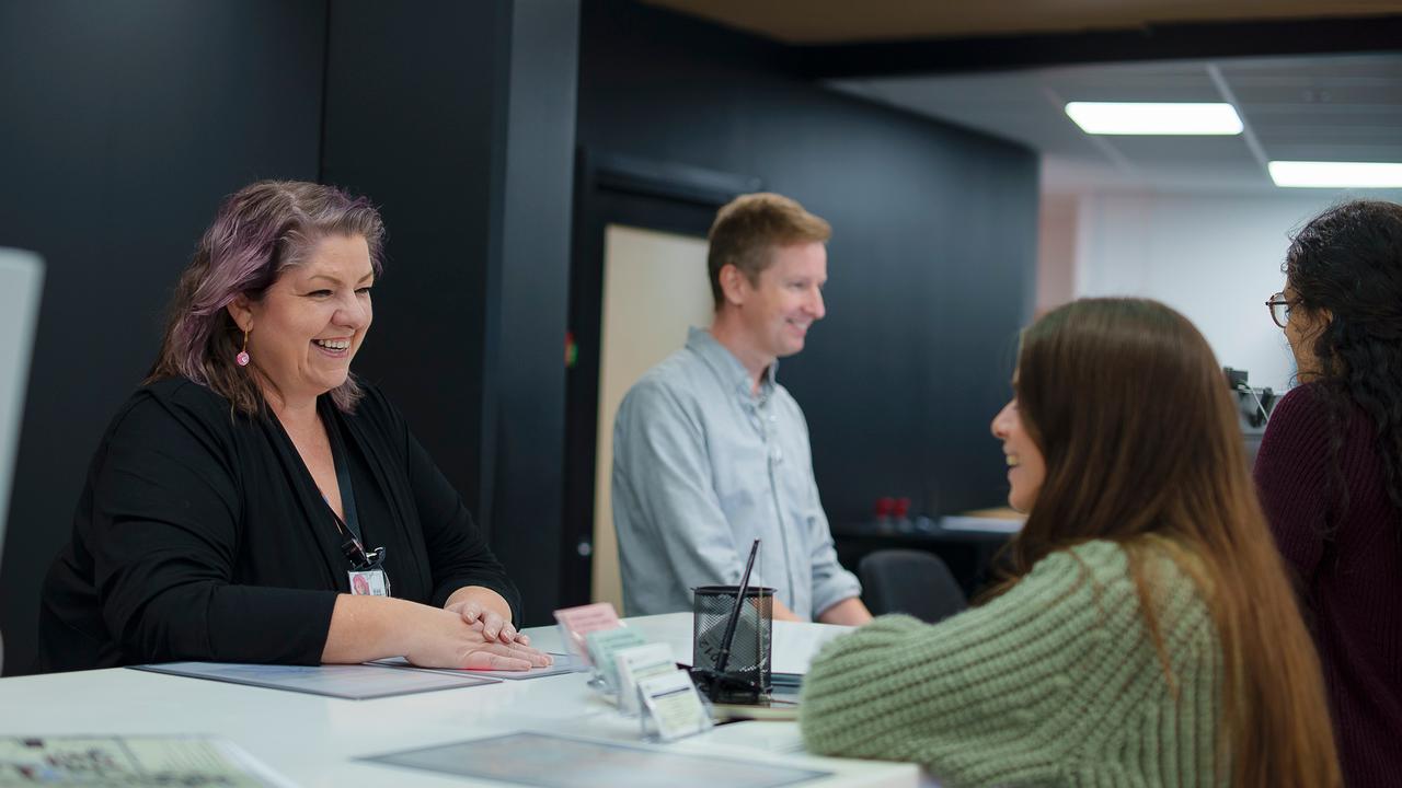 Staff welcoming new students and providing support at the infocenter service desk.