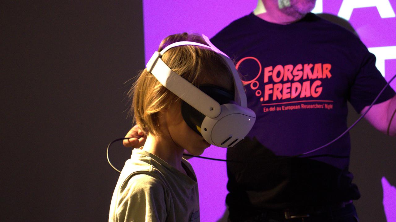 En ung pojke som bär ett par hörlurar medan han står bredvid en person.