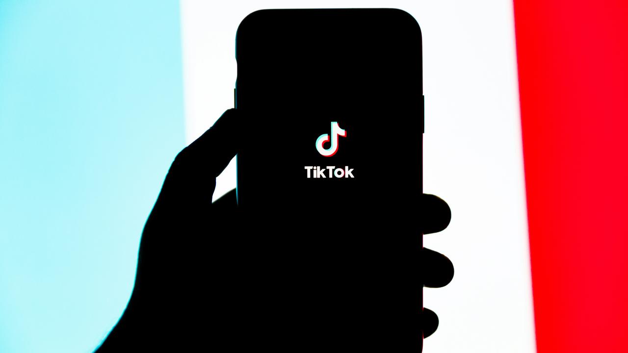 En person som håller en mobiltelefon i handen med Tiktok på.