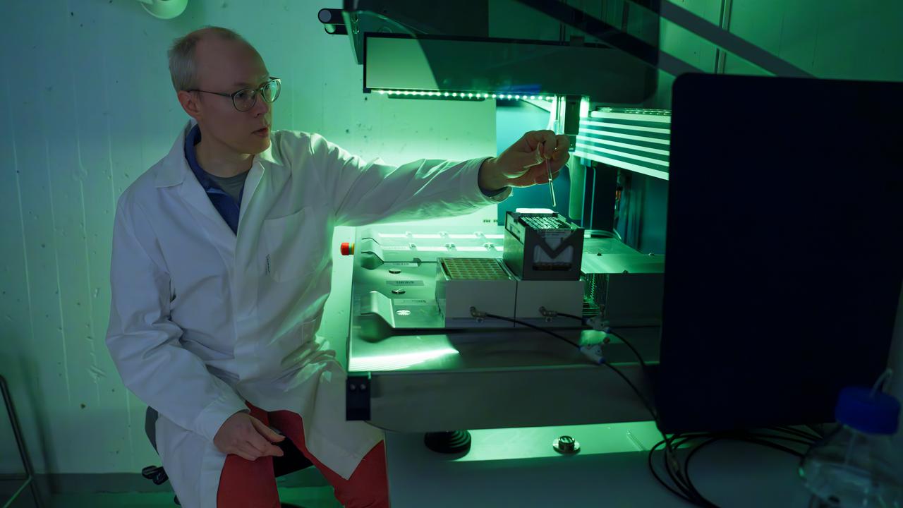 Person i labrock arbetar i grönt ljus.