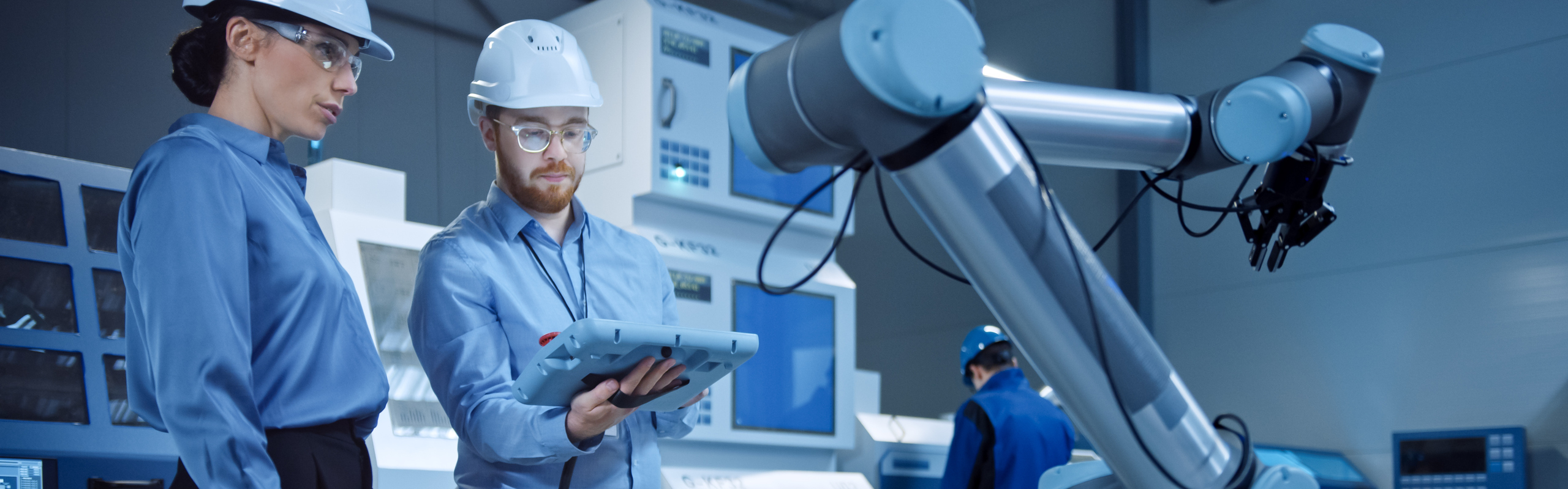 Bilden visar en kvinna och en man som arbetar med en robot.