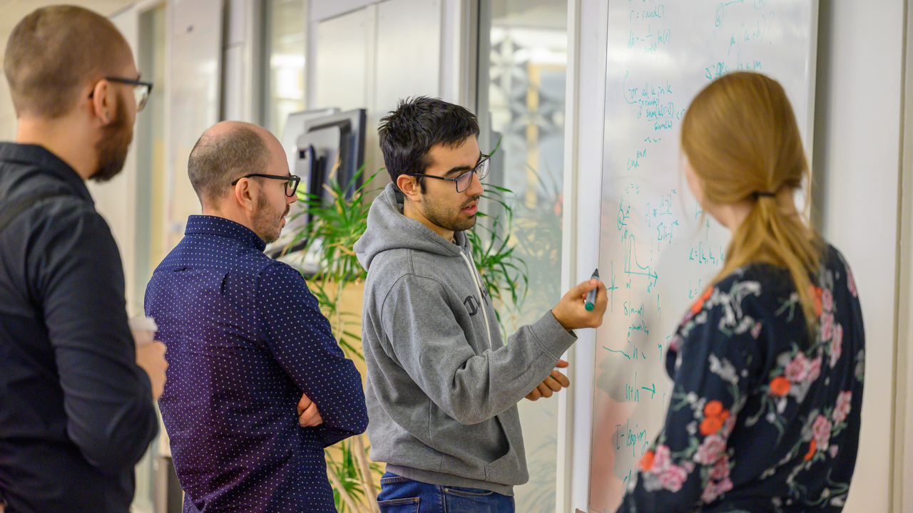 A group of people standing around a white board