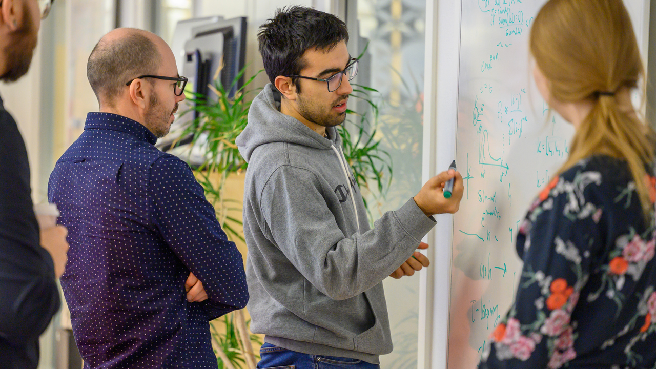 A group of people standing around a white board