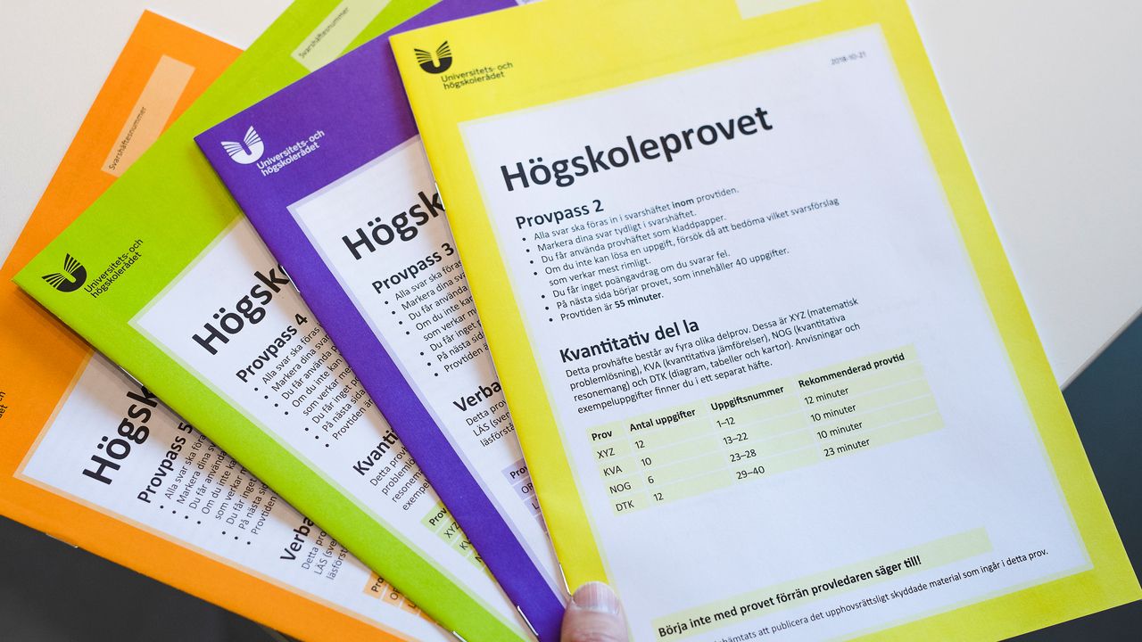 En hand håller ett antal högskoleprov.