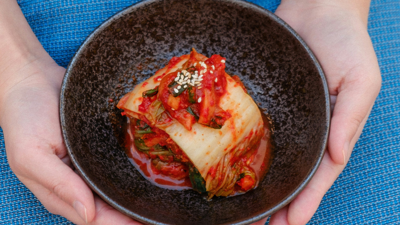 Händer som håller i en tallrik med fermenterad mat.