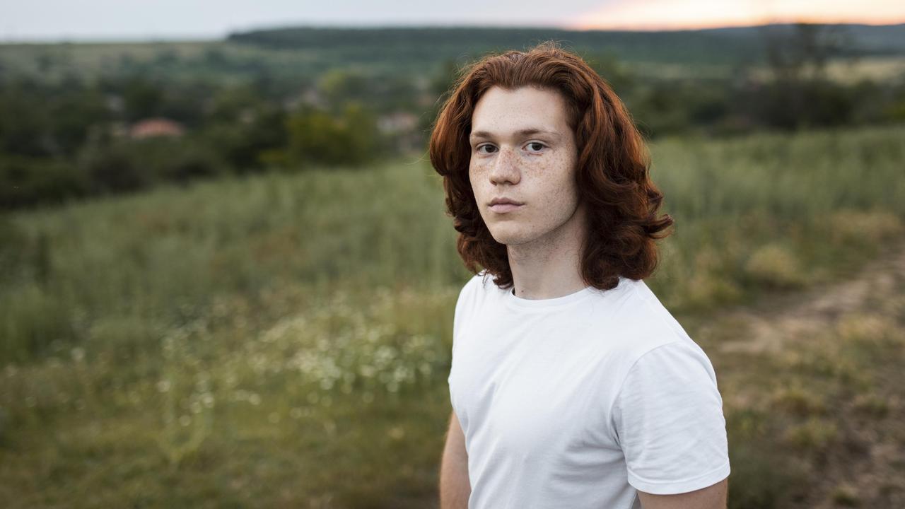 En man med rött hår står på ett fält.