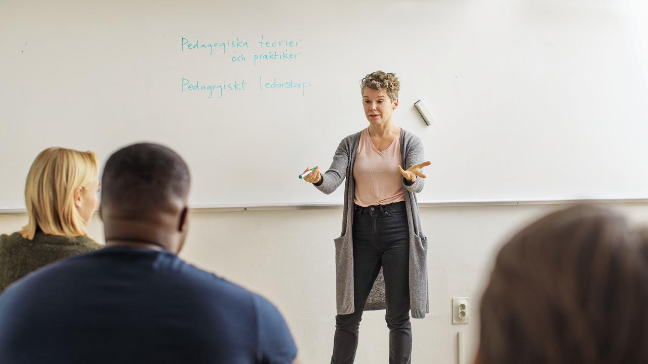 Lärare undervisar vuxna i klassrum.