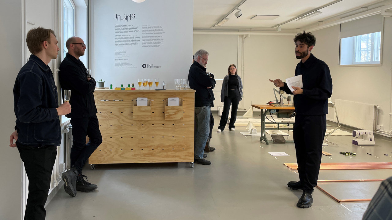 En forskare presenterar sitt projekt på en vernissage med publik.