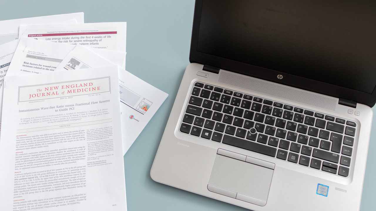 Vetenskapliga artiklar bredvid bärbar dator