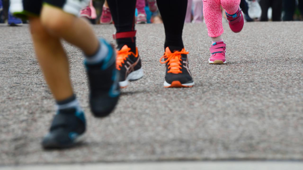 Fötter på personer i olika åldrar som springer på asfalt.