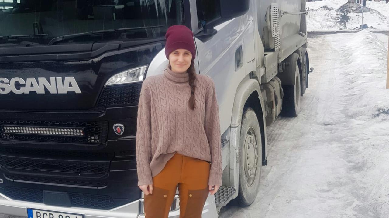 En kvinna som står framför en stor lastbil.