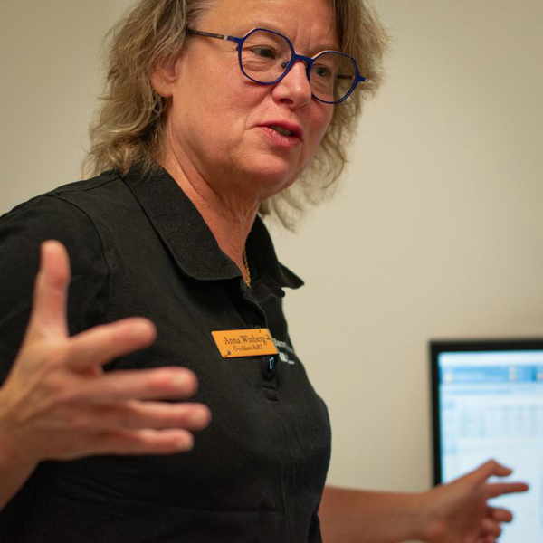 En kvinna i svart tröja pekar på en datorskärm.