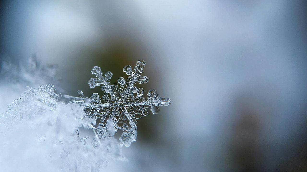 A close-up of a snowflake with a blurred background.