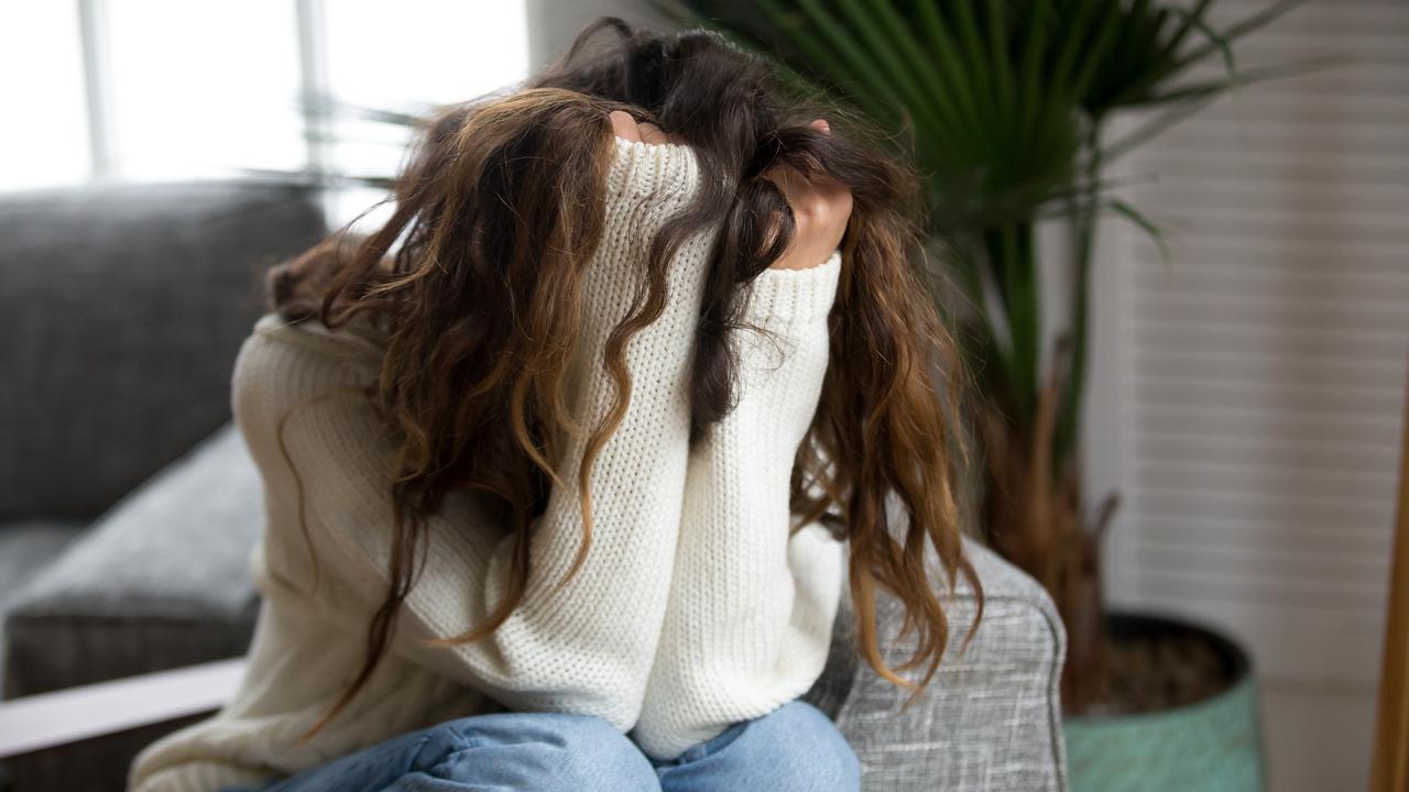 Kvinna som döljer sitt ansikte i sina händer. Ska illustrera psykisk ohälsa, depression, nedstämdhet eller liknande.